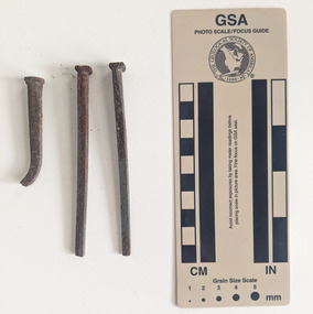 Three large rusted nails with a square head