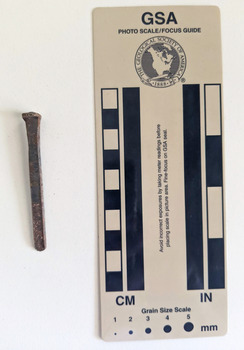 Corroded nail with a rose heads and rectangular shaft that narrow to a blunt tip.