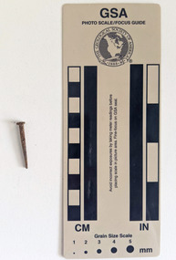 Corroded nail with a square shaft that narrows to a blunt tip.