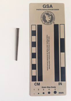 Corroded nail with a medium rectangular head and blunt tip.