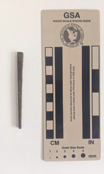 Corroded nail with a rectangular shaft narrowing to a pointed tip.
