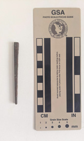 Corroded nail with a rectangular shaft narrowing to a pointed tip.