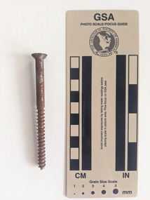 Corroded screw with grooves and a circular shaft narrowing to a pointed tip.