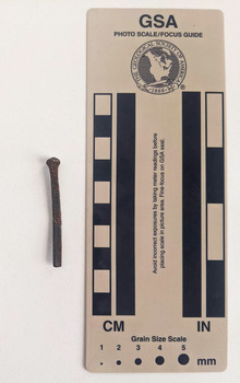 Corroded nail with rectangular shaft that narrows to a blunt tip.
