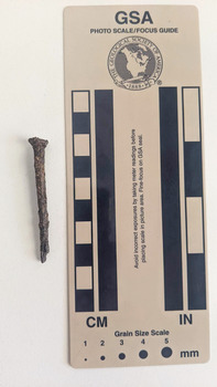 Corroded nail with rectangular shaft that narrows to a blunt tip.