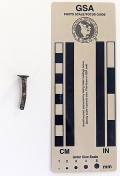 Corroded nail with rectangular shaft that narrows to a blunt tip.