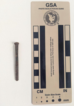 Corroded nail with rectangular shaft narrowing to a blunt tip. 