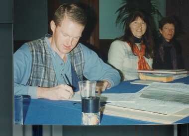 Photograph - Jeff Beer writing the incorporation document watched by Francesca Folk-Scolaro and Anne Laffan, Jun 1996