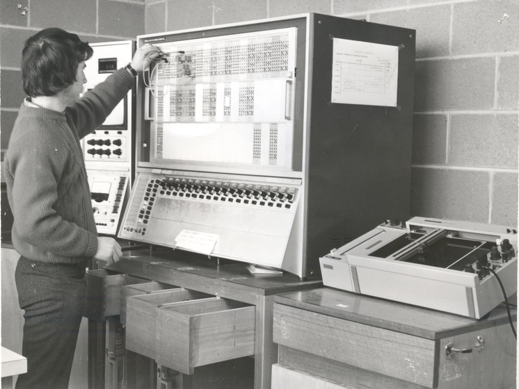 a man stands as he operates an old and large computer