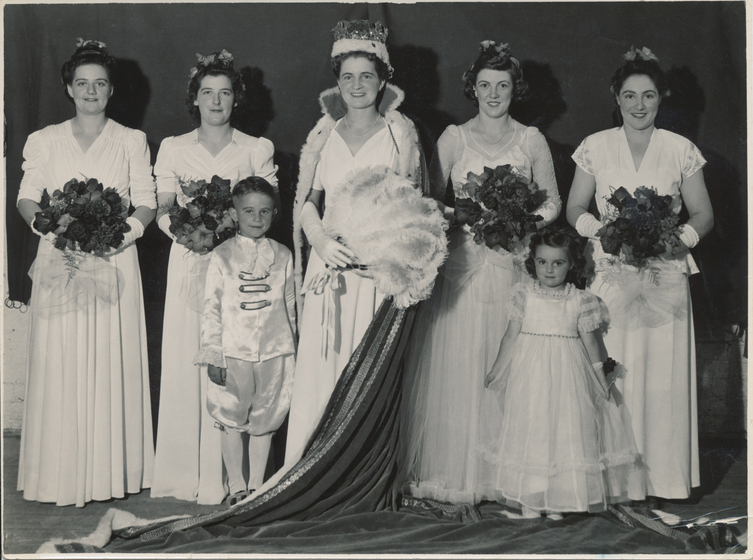five women in gowns stand with two children