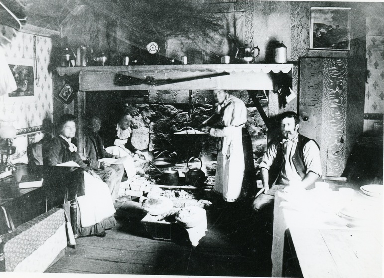 men and women around a kitchen in cabin
