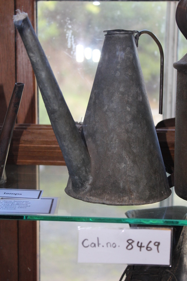 metal tallow lamp on glass shelf