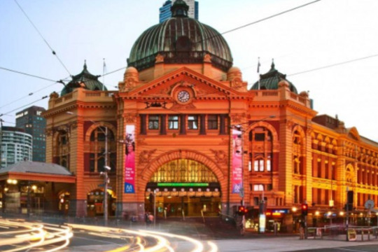 facade of train station with streaming lights from time-lapsed cars