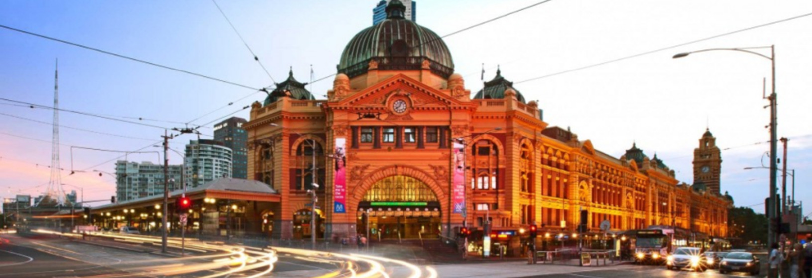 facade of train station with streaming lights from time-lapsed cars