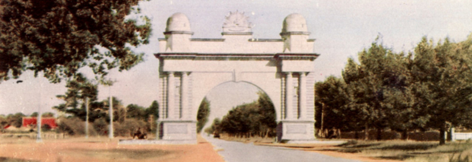 a grand arch reaches over a tree-lined road