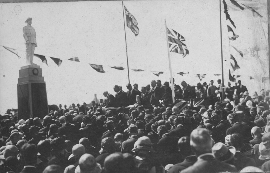 crowd gathered around memorial statue and flags