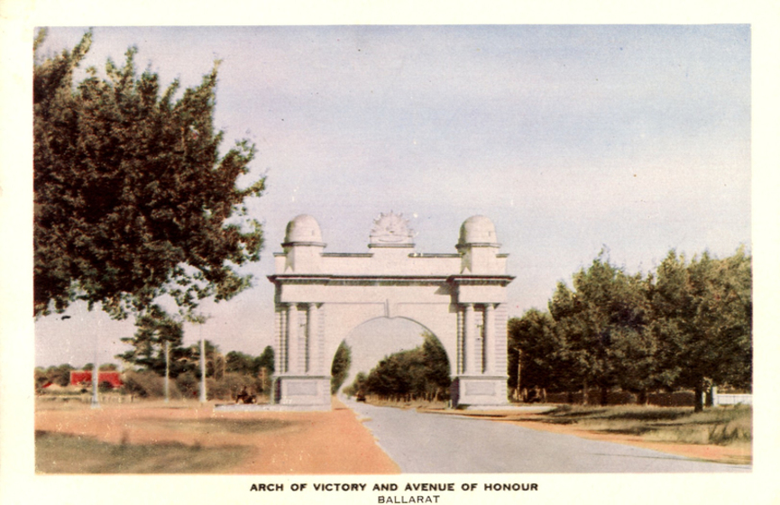 a grand arch reaches over a tree-lined road