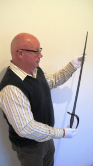 a man stands holding Captain Wilkinson's sword