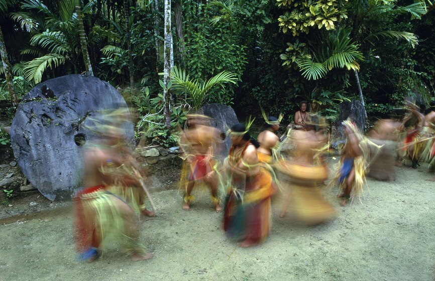 Dancers on an island in with a stone currency in the background