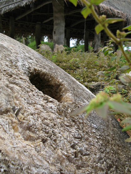 Large circular customary stone with a traditional building in the background