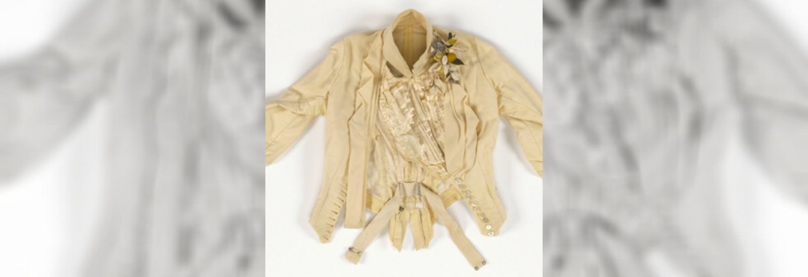 a close-up of the neck and shoulders of a wedding dress featuring a boutonnière