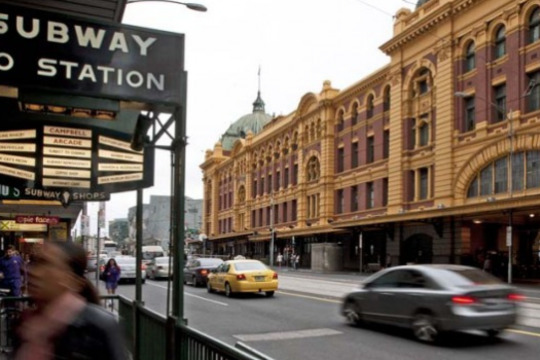 looking down Flinders Street with the station building opposite and the subway entrance ahead