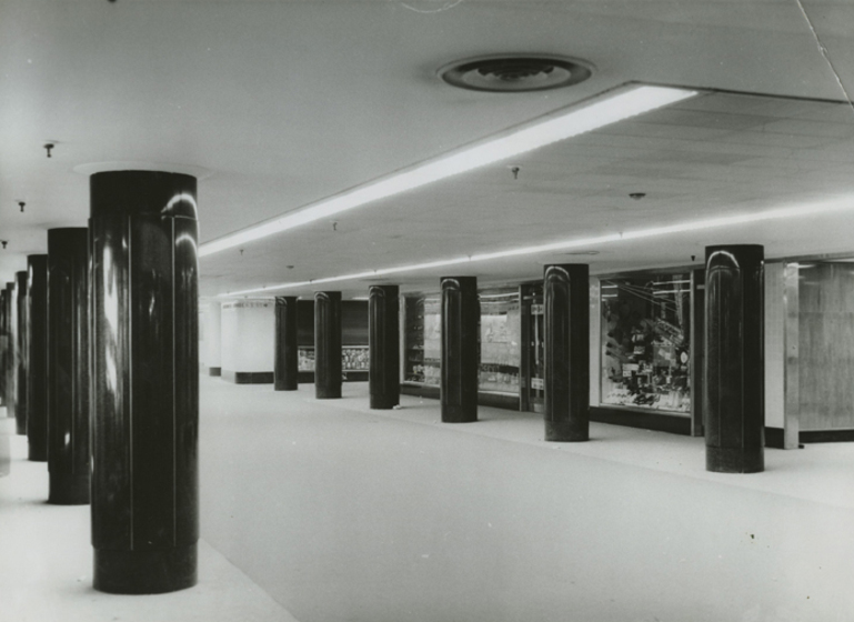 bold black pillars run along a corridor in black and white