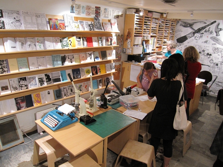 a bookshop with customers standing around a table doing activities