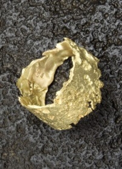 a hand-beaten gold ring sitting on stone