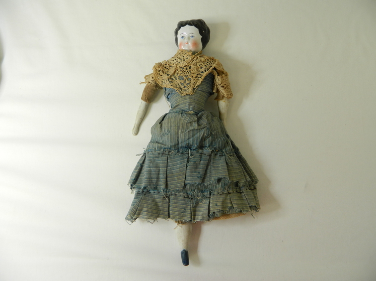 a porcelain doll in a cloth blue dress yellow shawl