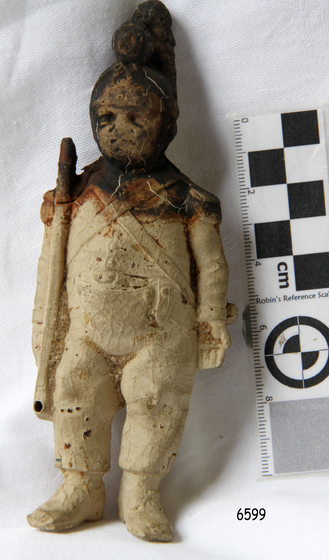 a very old male figure, dressed as soldier with blackened head