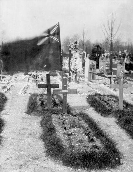 monochrome image of grave in cemetery with flag