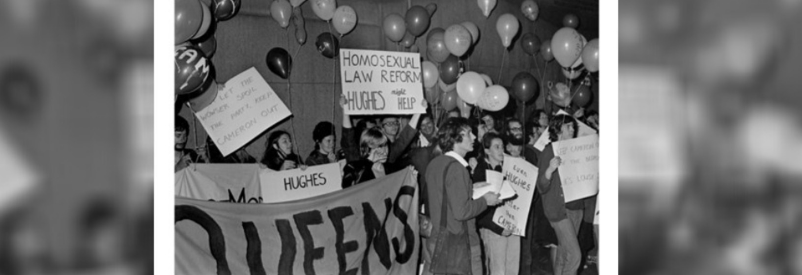 crowd holding banners and signs, balloons in the background