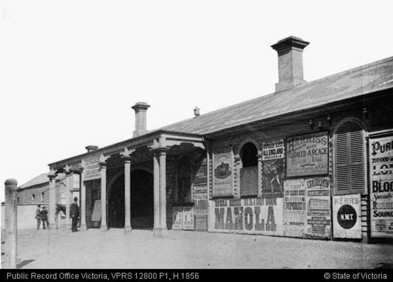 a very old station railway station, festooned with signage and three men stand at the entry