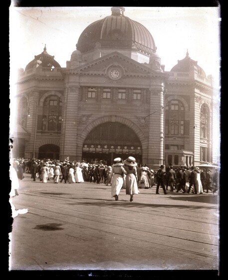 outside of Flinders Street railway station with crowds of men and women arriving and departing