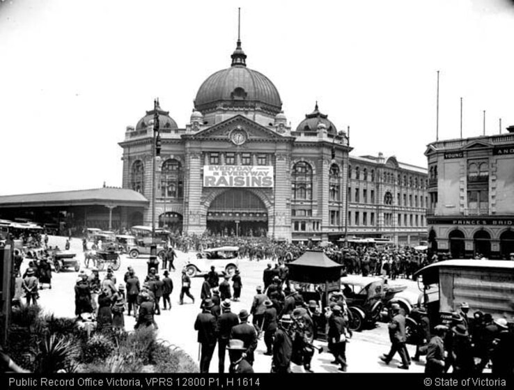 the front facade of Flinders Station with crowds of visitors and old horse-drawn carriages