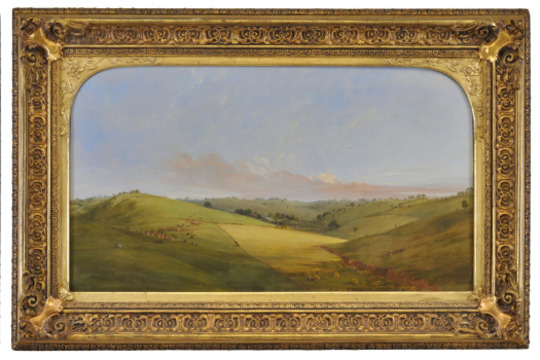 rolling grassy hills with a homestead in the distance and a flock of sheep in the foreground