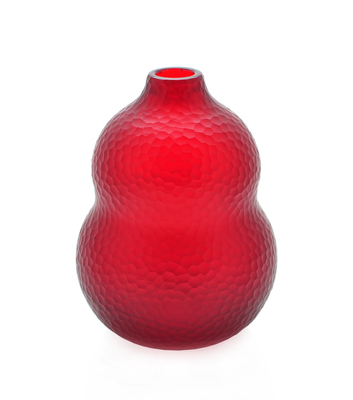a modernist red glass vase, the surface of which has been ground to create a bees nest pattern.