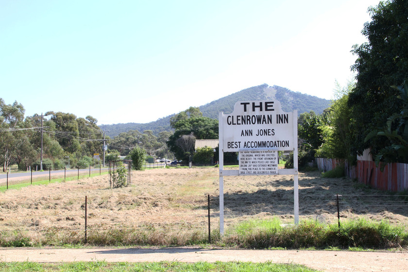 A replica signboard 'The Glenrowan Inn, Anne Jones, best accommodation' marking the where the hotel once stood showing more of the town block andwith hillside surrounds