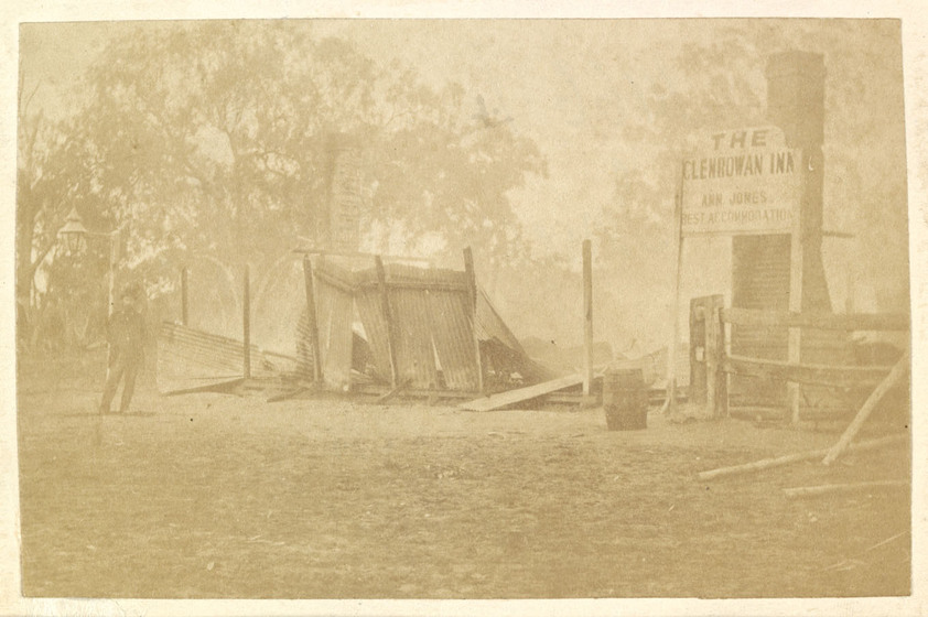 Man standing next to the remains of the burnt down Glenrowan Inn. Period image, sepia toned