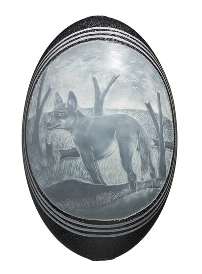 a circular carved image of a dingo standing in a barren forest, includes three additional liner circles carved on the outer edge