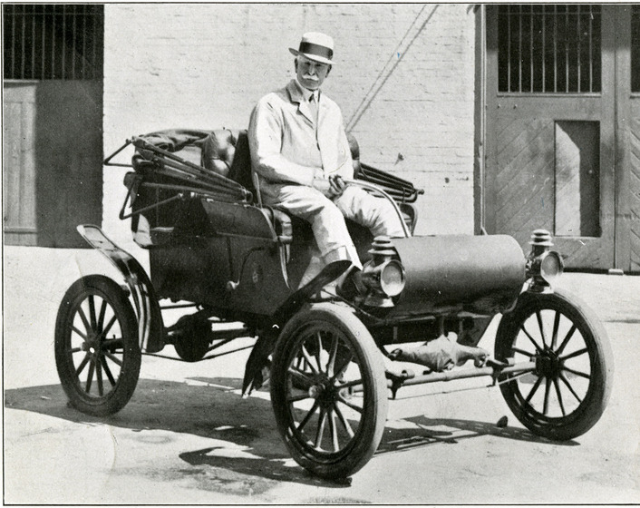 Man sitting in the driver's seat of an old model car
