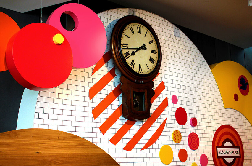 a wooden clock mounted on colourful wall
