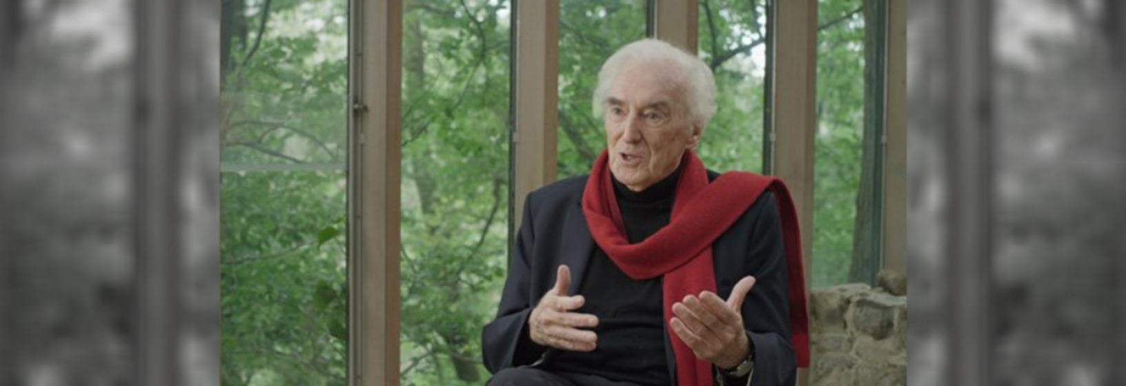 Man with red scarf talks to camera