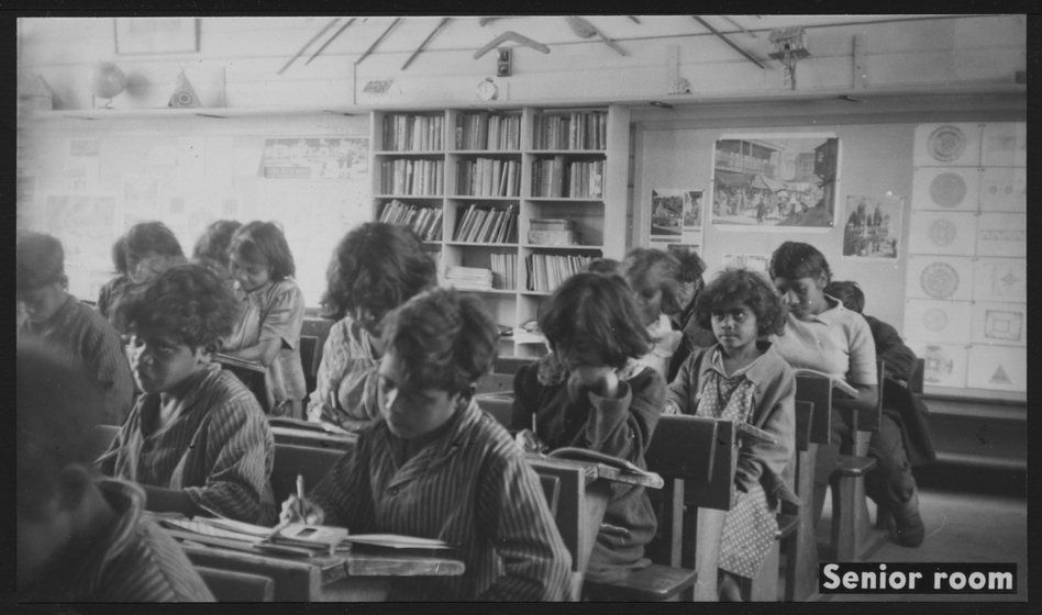a black and white photograph of school students working at desks.