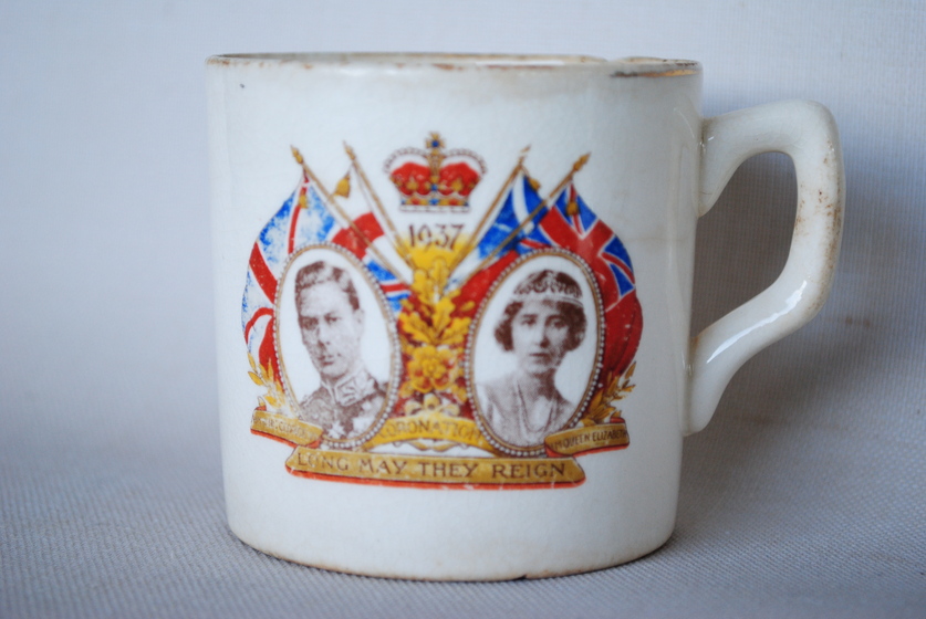 Mug with two portraits with flags seen behind and crown in between