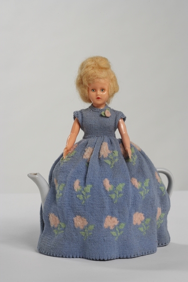 Knitted tea cosy, blonde doll in blue dress