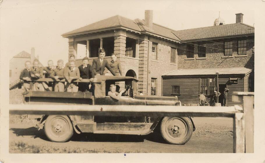 Children riding in car in front of house