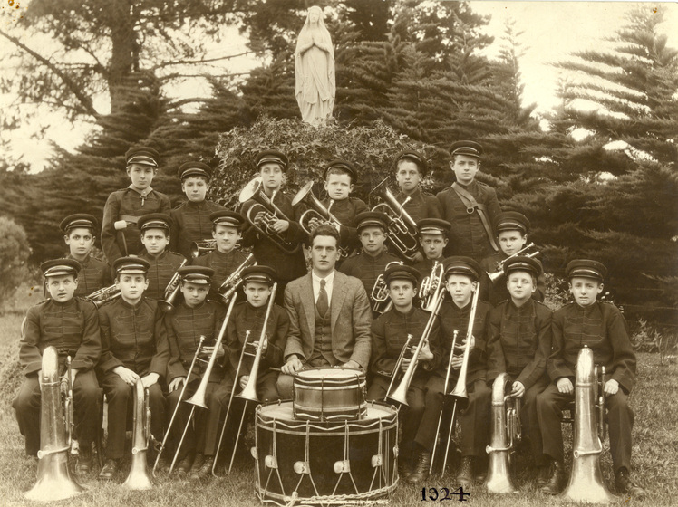 Group of children and one man in band uniform with instruments