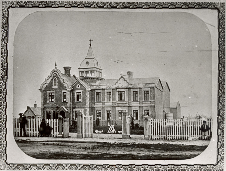 Image of large house behind fence with ornate border